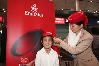 阿联酋航空地勤人员为参加首发团的小游客配戴Fly Emirates纪念帽